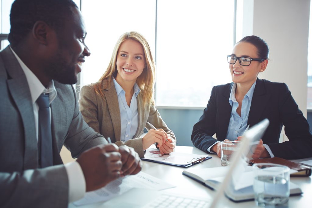 Happy businesswomen listening to young man explanations
