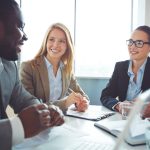 Happy businesswomen listening to young man explanations